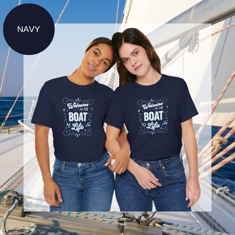 Navy t-shirt with a decorative design featuring the phrase 'Welcome to the Boat Life' in a mix of bold and cursive fonts, accented with nautical-themed swirls and sparkles.