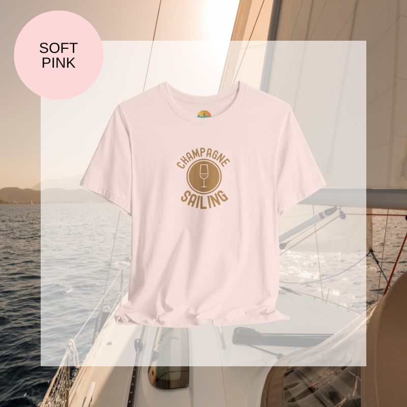 Soft pink t-shirt featuring a minimalist design with the text 'Champagne Sailing' in elegant gold lettering and a simple champagne glass icon, perfect for lovers of luxurious sailing vibes.