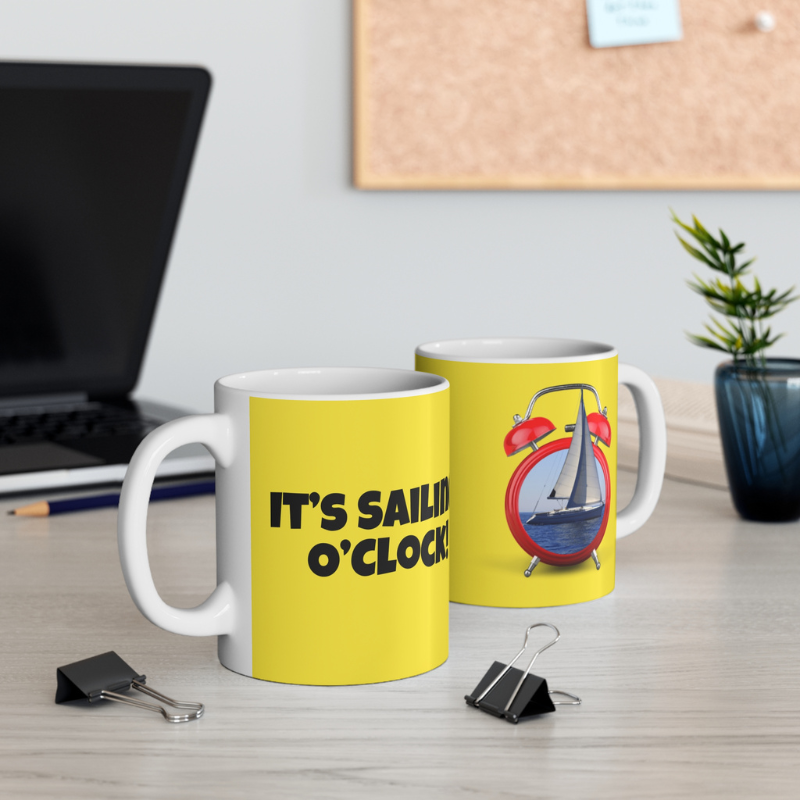 Bright yellow coffee mug featuring the playful text 'It's Sailing O'Clock!' and an alarm clock design with a sailboat inside, perfect for sailing enthusiasts ready to set sail at any time