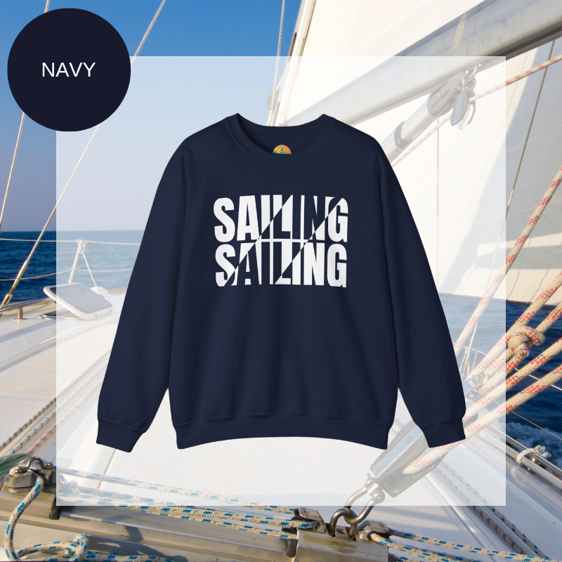 A navy men's sweatshirt with a bold white "SAILING" split text design, displayed against a sailing yacht background.