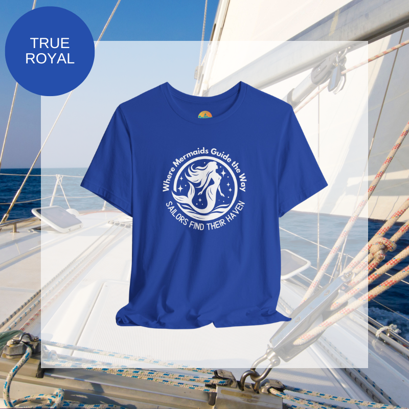 Royal blue unisex t-shirt featuring a whimsical mermaid design with the text 'Where Mermaids Guide the Way, Sailors Find Their Haven,' displayed on a yacht deck background.