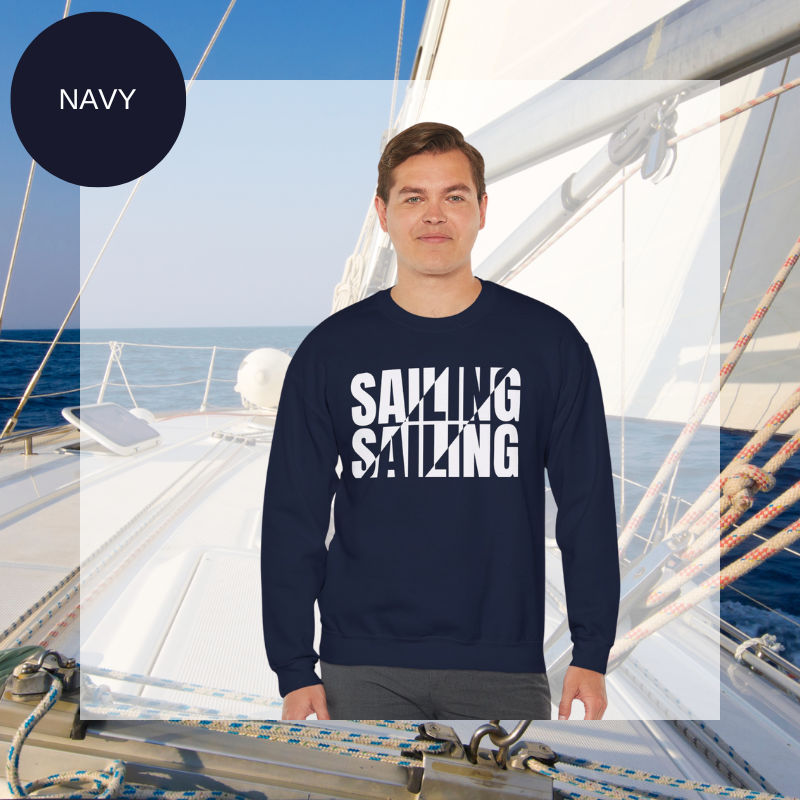A navy men's sweatshirt with a bold white "SAILING" split text design, displayed against a sailing yacht background.