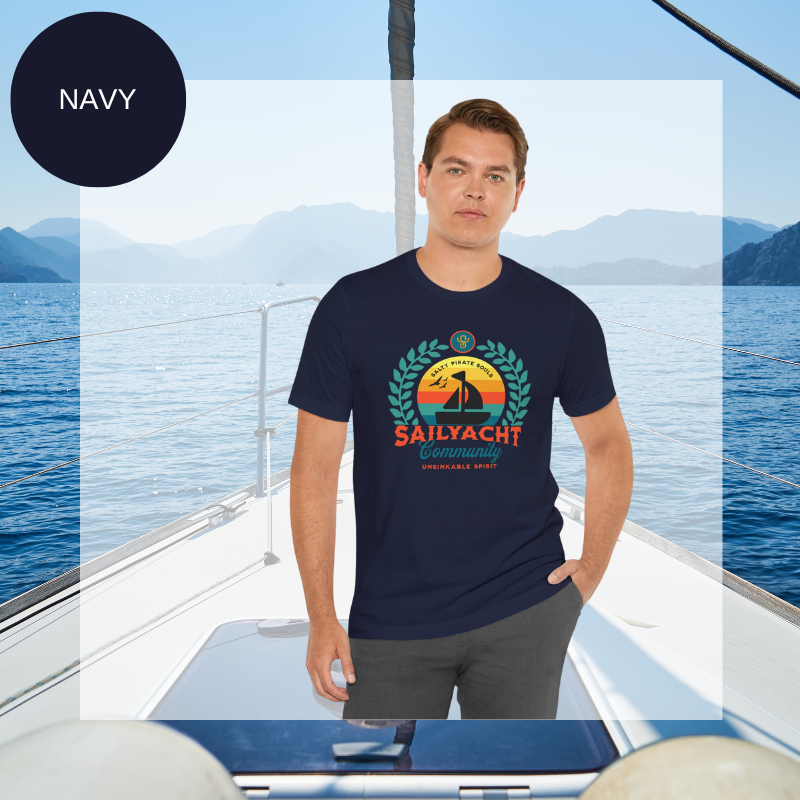 Navy blue unisex t-shirt featuring a vibrant 'Sailyacht Community' design with a sailboat, laurel wreath, and retro sunset, displayed on a yacht deck background.