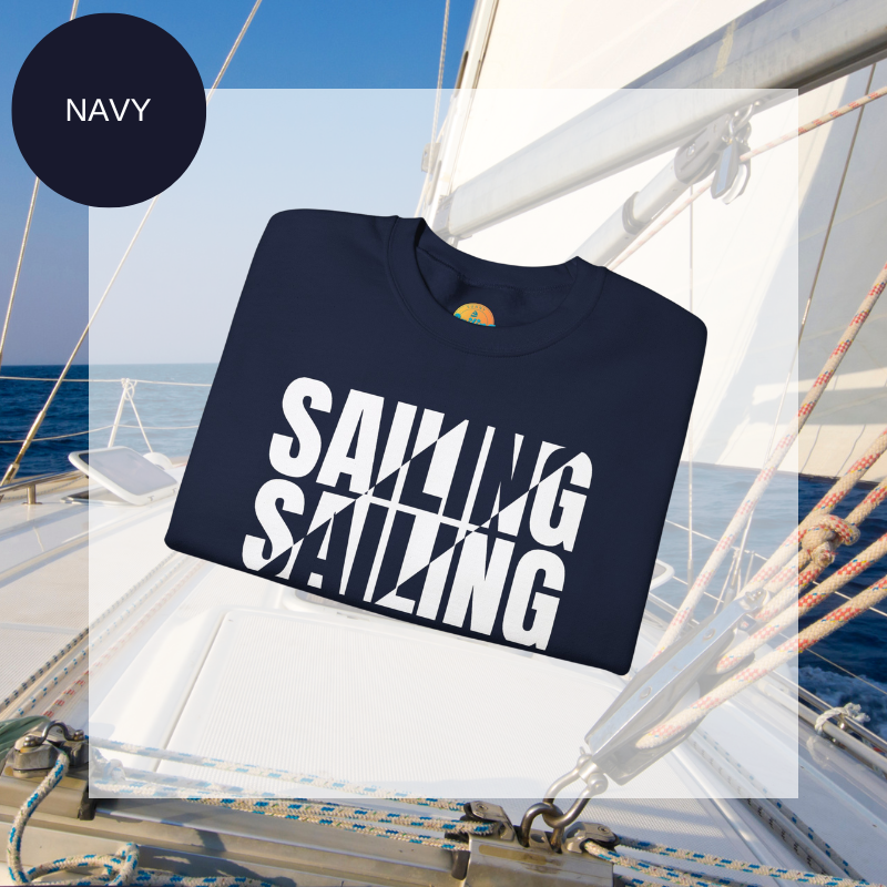 A navy men's sweatshirt with a bold white "SAILING" split text design, displayed against a sailing yacht background.