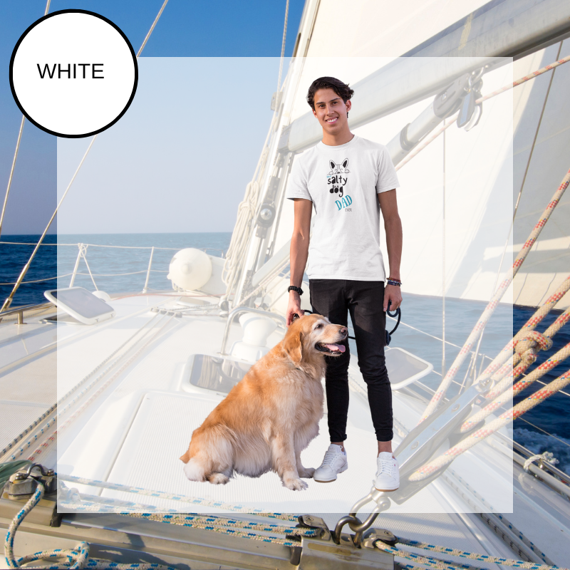 White t-shirt featuring the text 'Best Salty Dog Dad Ever' in playful fonts. The design includes an illustration of a cute dog's face peeking over the words, combining nautical and pet-loving themes. The background showcases a serene sailing scene with ropes and a yacht deck.