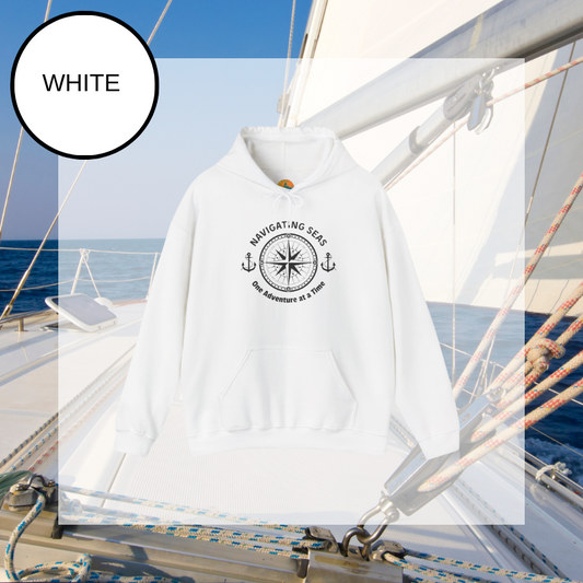 White hoodie featuring a nautical compass and anchor design with the text 'Navigating Seas - One Adventure at a Time,' perfect for sailors and ocean enthusiasts.