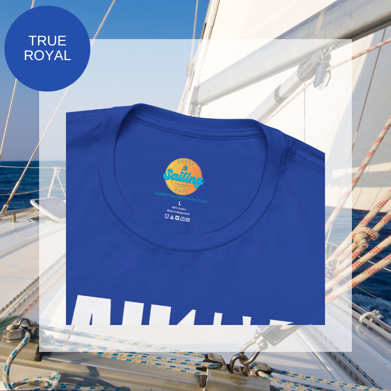 Royal blue unisex t-shirt with bold white text design reading 'Sailing Sailing,' displayed on a yacht deck with a nautical background.