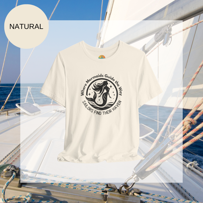 Natural white unisex t-shirt featuring a whimsical mermaid design with the text 'Where Mermaids Guide the Way, Sailors Find Their Haven,' displayed on a yacht deck background.