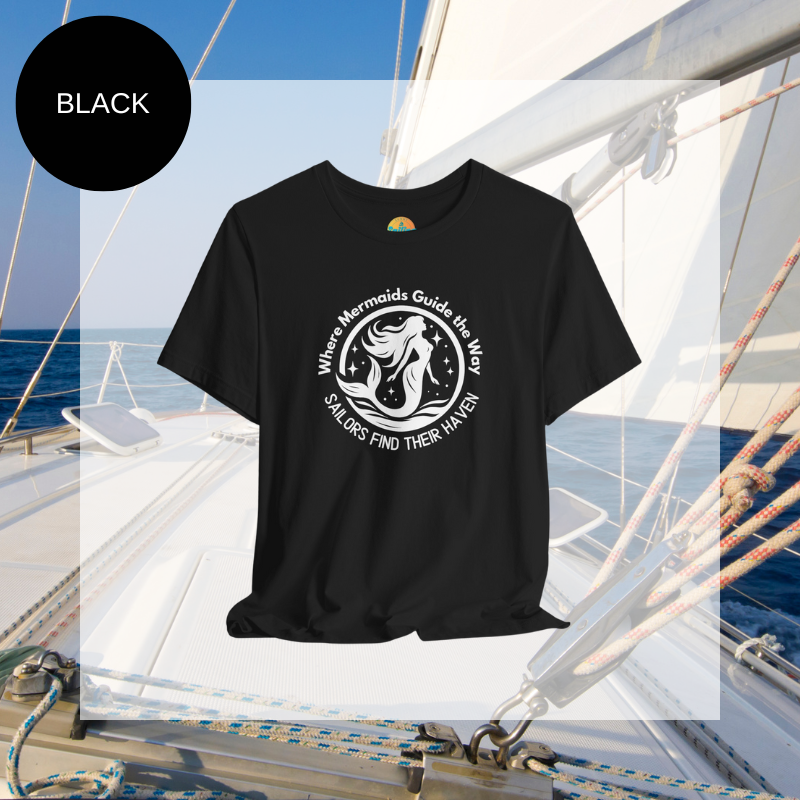 Black unisex t-shirt featuring a whimsical mermaid design with the text 'Where Mermaids Guide the Way, Sailors Find Their Haven,' displayed on a yacht deck background.