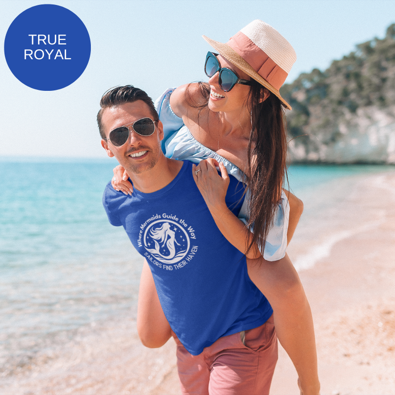 Royal blue unisex t-shirt featuring a whimsical mermaid design with the text 'Where Mermaids Guide the Way, Sailors Find Their Haven,' displayed on a yacht deck background.