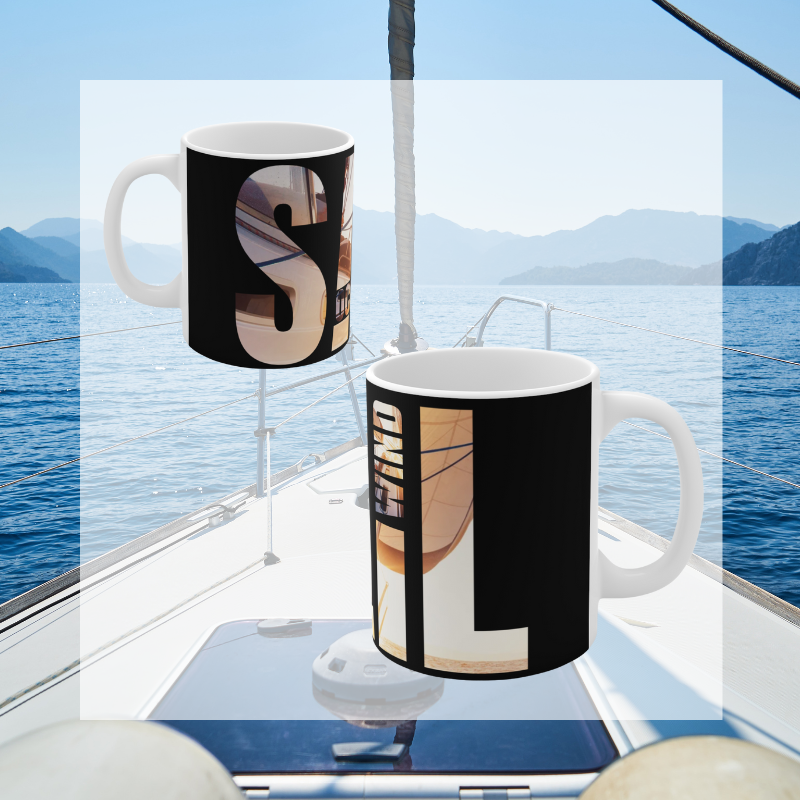 Black coffee mug with bold typography spelling 'SAIL OCEAN WIND,' featuring a vibrant image of a sailboat bathed in warm sunlight, perfect for sailing enthusiasts.