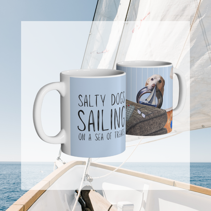 Light blue coffee mug featuring the text 'Salty Dogs Sailing on a Sea of Treats' with a playful illustration of a dog holding a food bowl with a sailboat in it, perfect for dog-loving sailors.