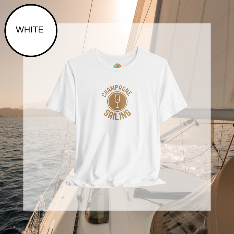 Soft pink t-shirt featuring a minimalist design with the text 'Champagne Sailing' in elegant gold lettering and a simple champagne glass icon, perfect for lovers of luxurious sailing vibes.