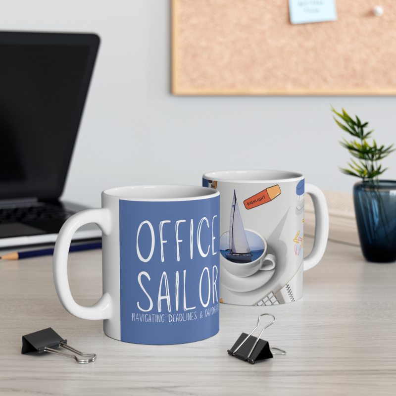 Blue coffee mug with the text 'Office Sailor: Navigating Deadlines & Daydreams,' featuring a playful design of a sailboat inside a coffee cup, perfect for combining work vibes with sailing dreams