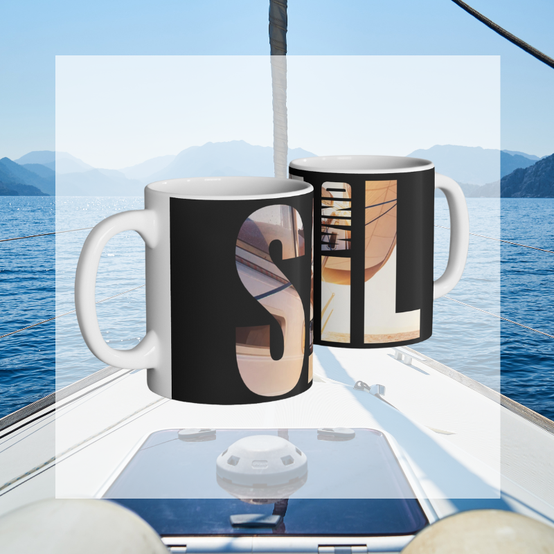 Black coffee mug with bold typography spelling 'SAIL OCEAN WIND,' featuring a vibrant image of a sailboat bathed in warm sunlight, perfect for sailing enthusiasts.