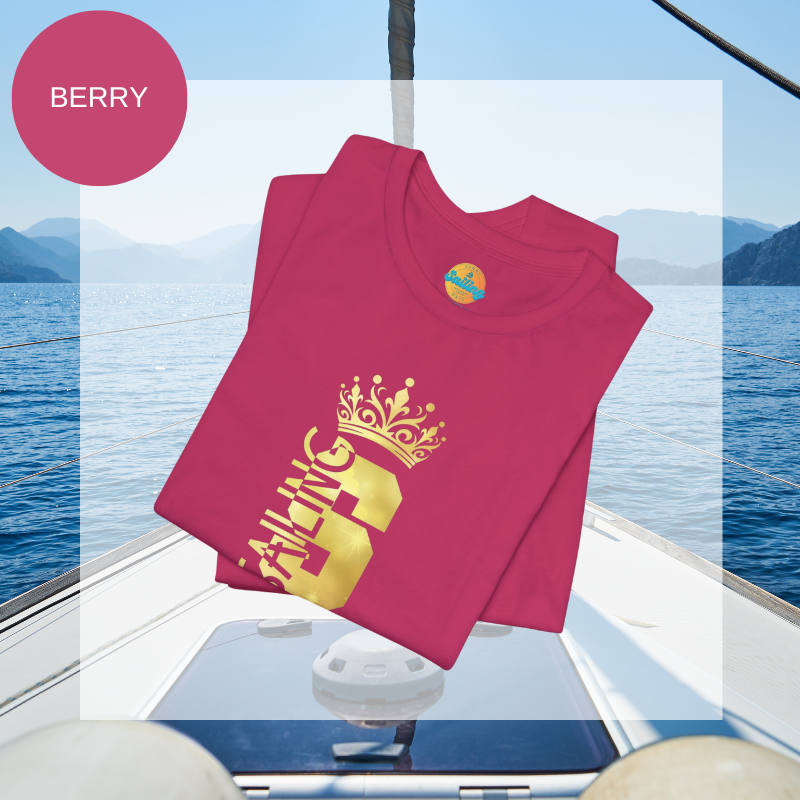 Berry-colored t-shirt with a gold crown graphic and the word 'SAILING' written vertically within the bold letter 'S', creating a regal and nautical-themed design.