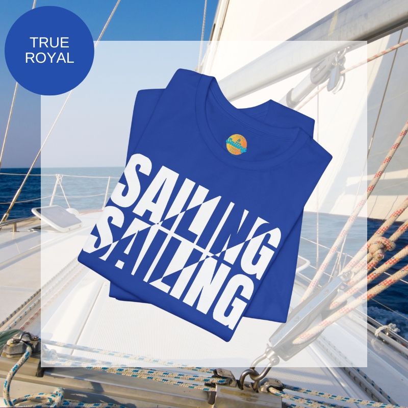 Royal blue unisex t-shirt with bold white text design reading 'Sailing Sailing,' displayed on a yacht deck with a nautical background.