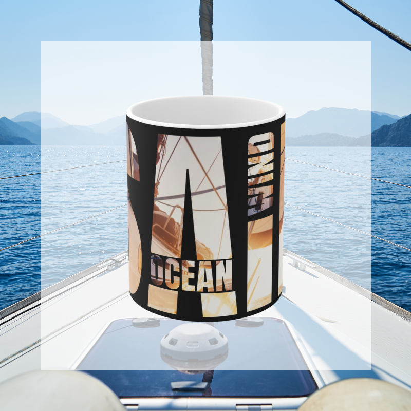 Black coffee mug with bold typography spelling 'SAIL OCEAN WIND,' featuring a vibrant image of a sailboat bathed in warm sunlight, perfect for sailing enthusiasts.