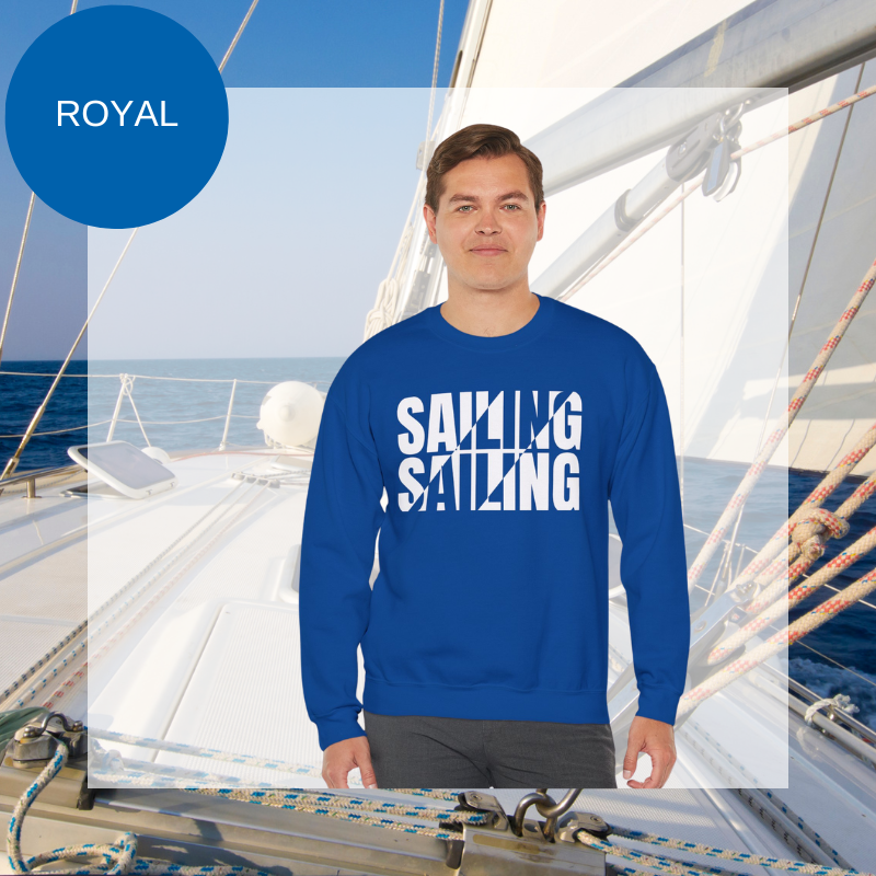 A royal blue men's sweatshirt with a bold white "SAILING" split text design, displayed against a sailing yacht background.