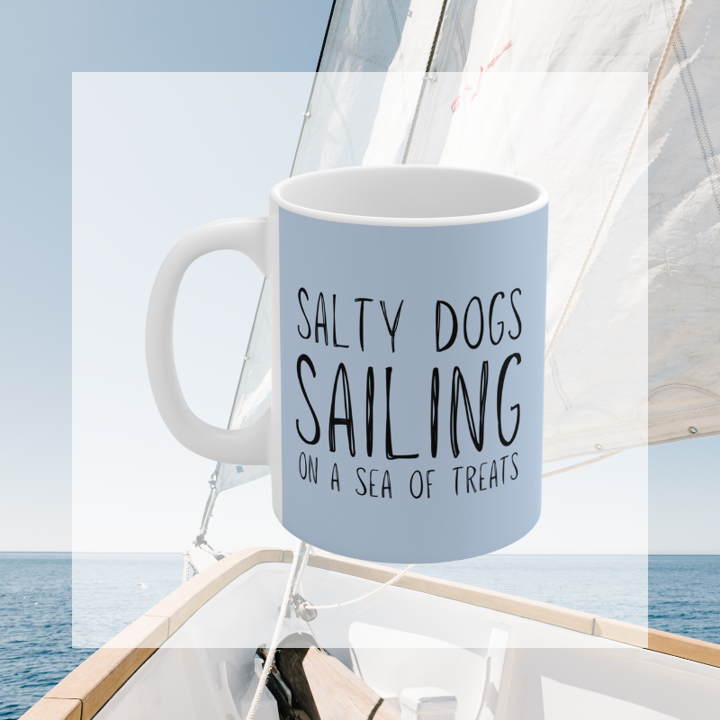 Light blue coffee mug featuring the text 'Salty Dogs Sailing on a Sea of Treats' with a playful illustration of a dog holding a food bowl with a sailboat in it, perfect for dog-loving sailors.