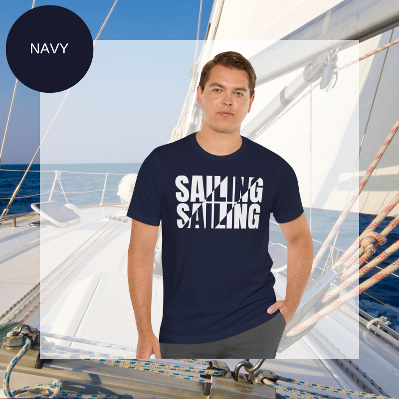 Navy unisex t-shirt with bold white text design reading 'Sailing Sailing,' displayed on a yacht deck with a nautical background.