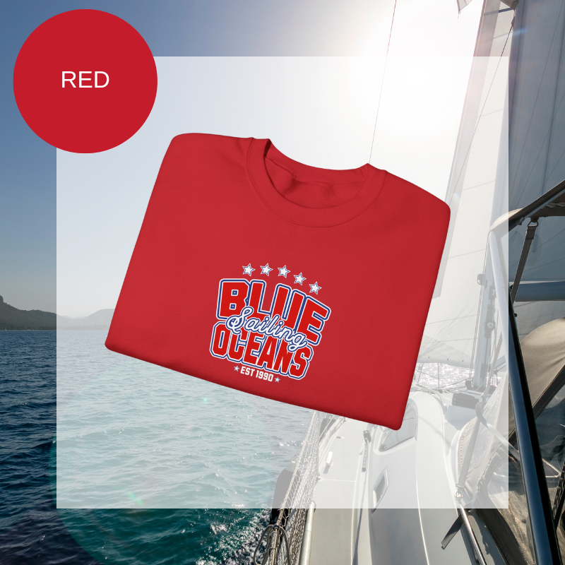 Red women's sweatshirt with a bold "Blue Oceans Sailing" print, featuring stars and a nautical-inspired design, displayed against a sailing-themed background.