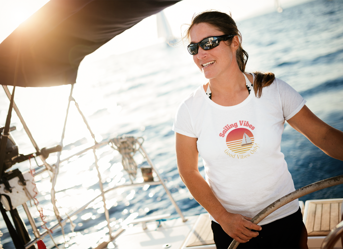 woman steering a sailingboat wearing a white t-shirt wih print Sailing Vibes good vibes only