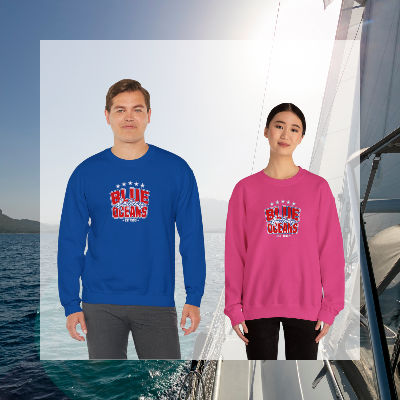 Navy blue and pink sweatshirt featuring the text 'Blue Sailing Oceans - Est. 1990' in bold red and white with star accents, perfect for nautical enthusiasts.