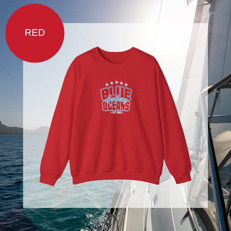 Red women's sweatshirt with a bold "Blue Oceans Sailing" print, featuring stars and a nautical-inspired design, displayed against a sailing-themed background.