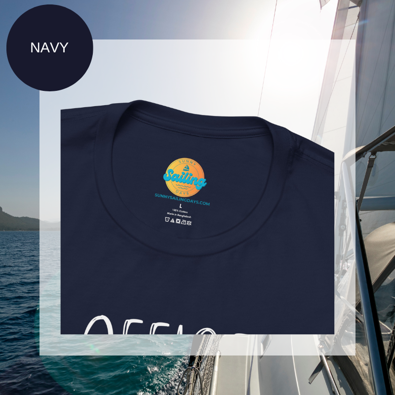 Navy women's t-shirt with the text 'Office Sailor: Navigating Deadlines & Daydreams' and colorful paperclip illustrations, displayed on a sailing-themed background.